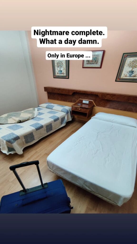 Small budget hotel room in Antequera with two beds and a blue suitcase