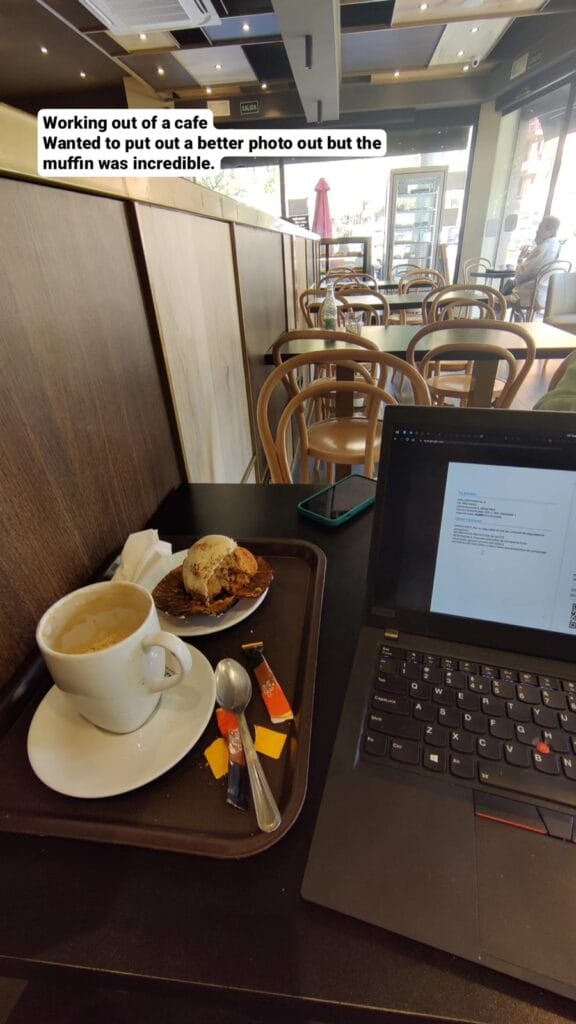 Open laptop and a cappuccino on a cafe table in Barcelona while working remotely