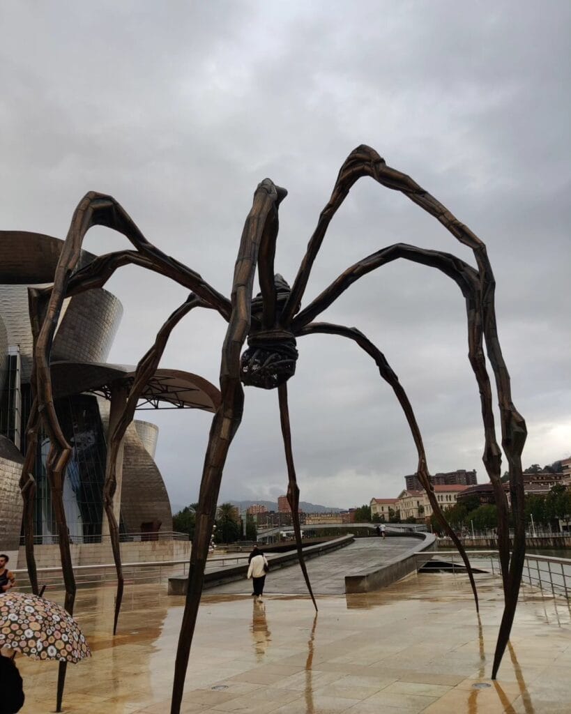 Louise Bourgeois' giant spider Maman beside the titanium Guggenheim Bilbao on a wet plaza