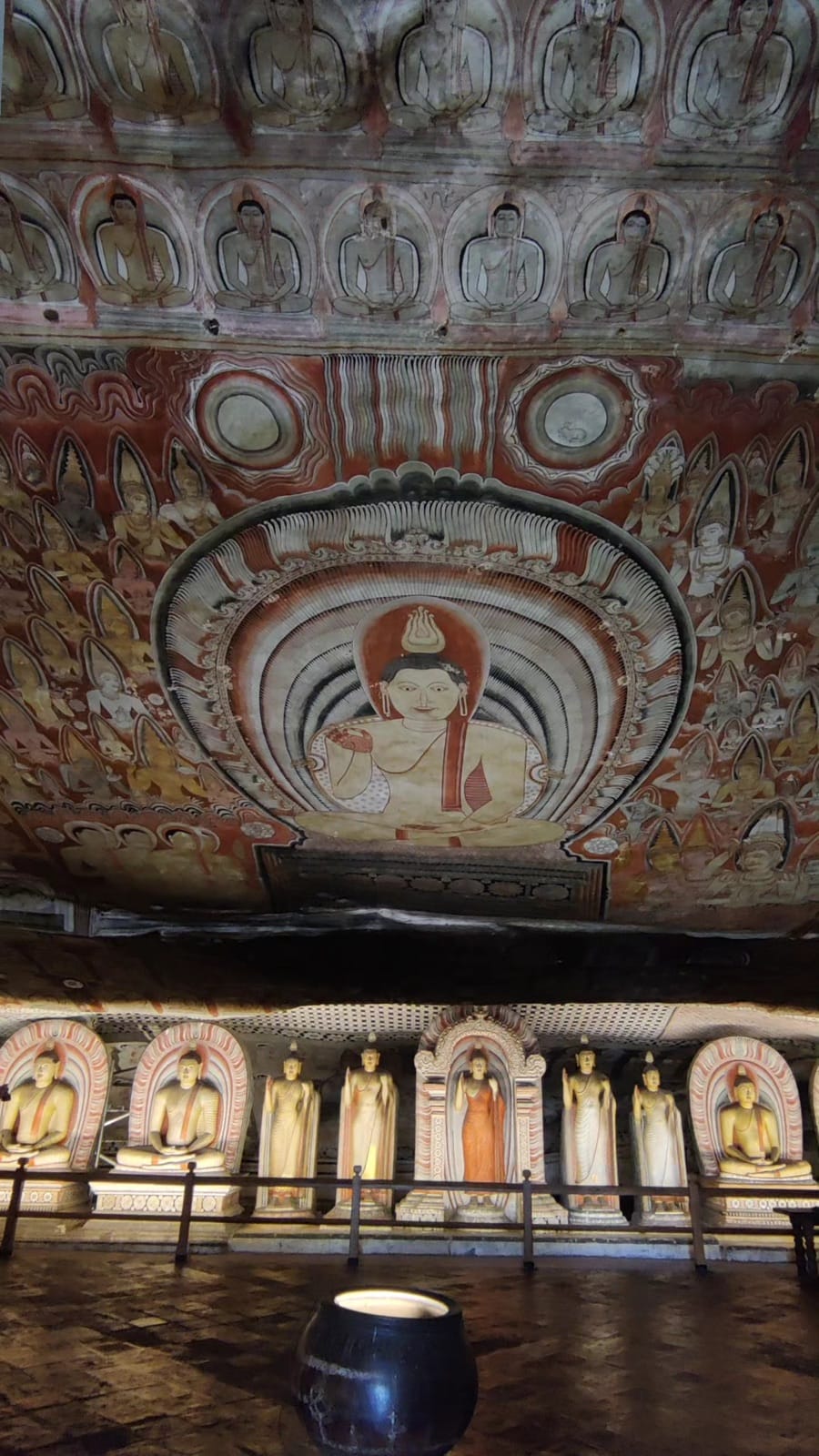 Painted cave ceiling flowing over a row of Buddha statues at Dambulla cave temple