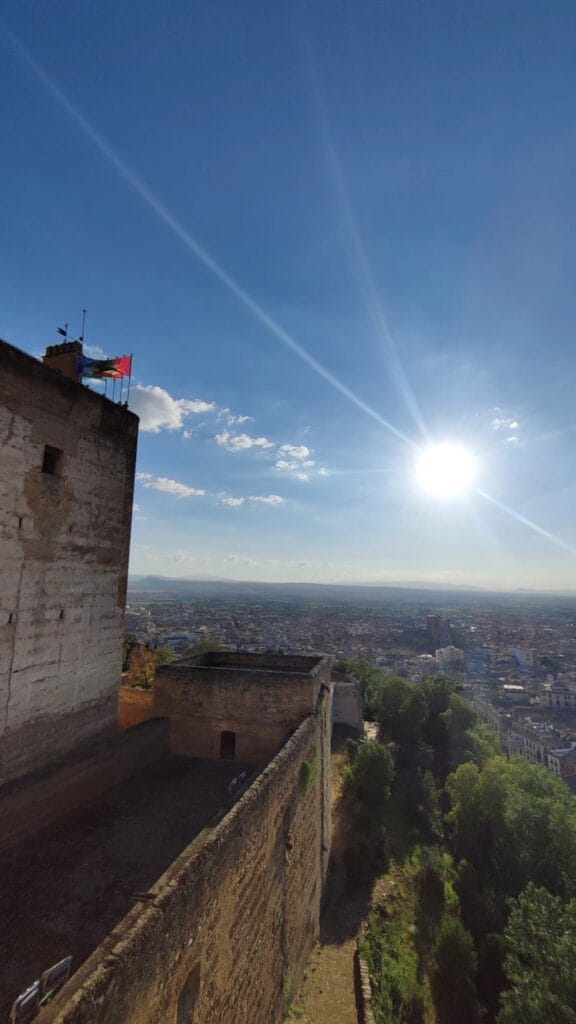 Alcazaba watchtower of the Alhambra with the Spanish flag and the Granada vega beyond