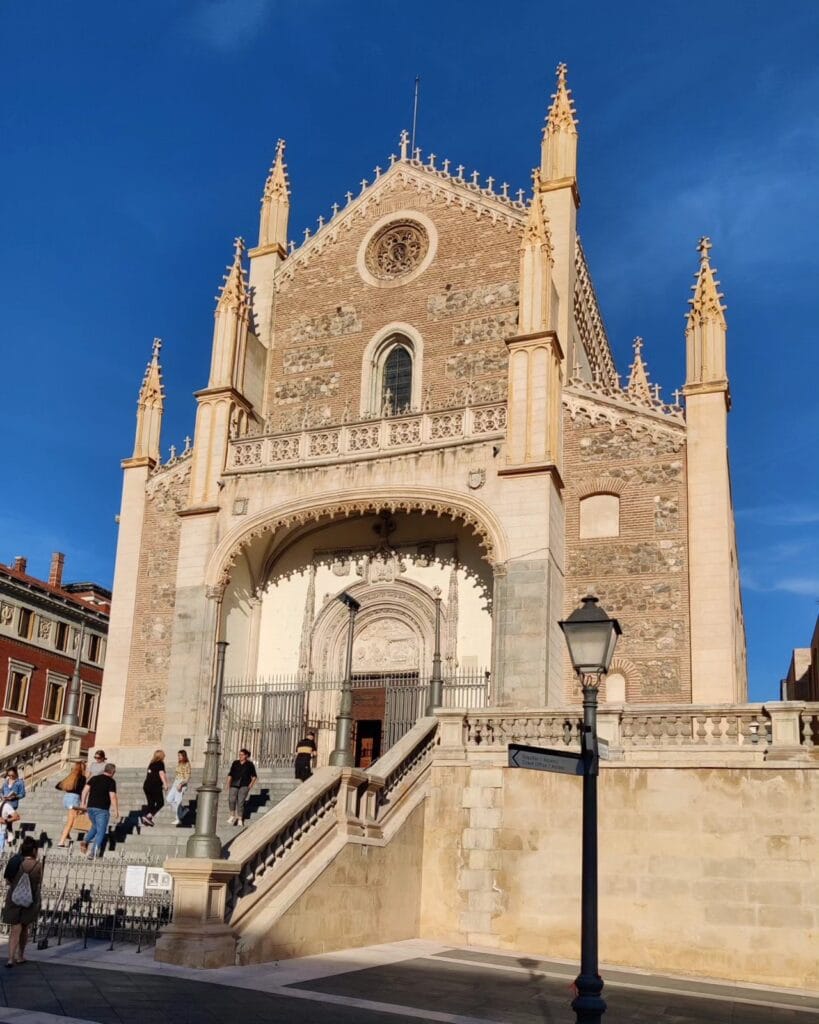 Gothic twin-towered facade of San Jeronimo el Real against a deep blue sky, Madrid