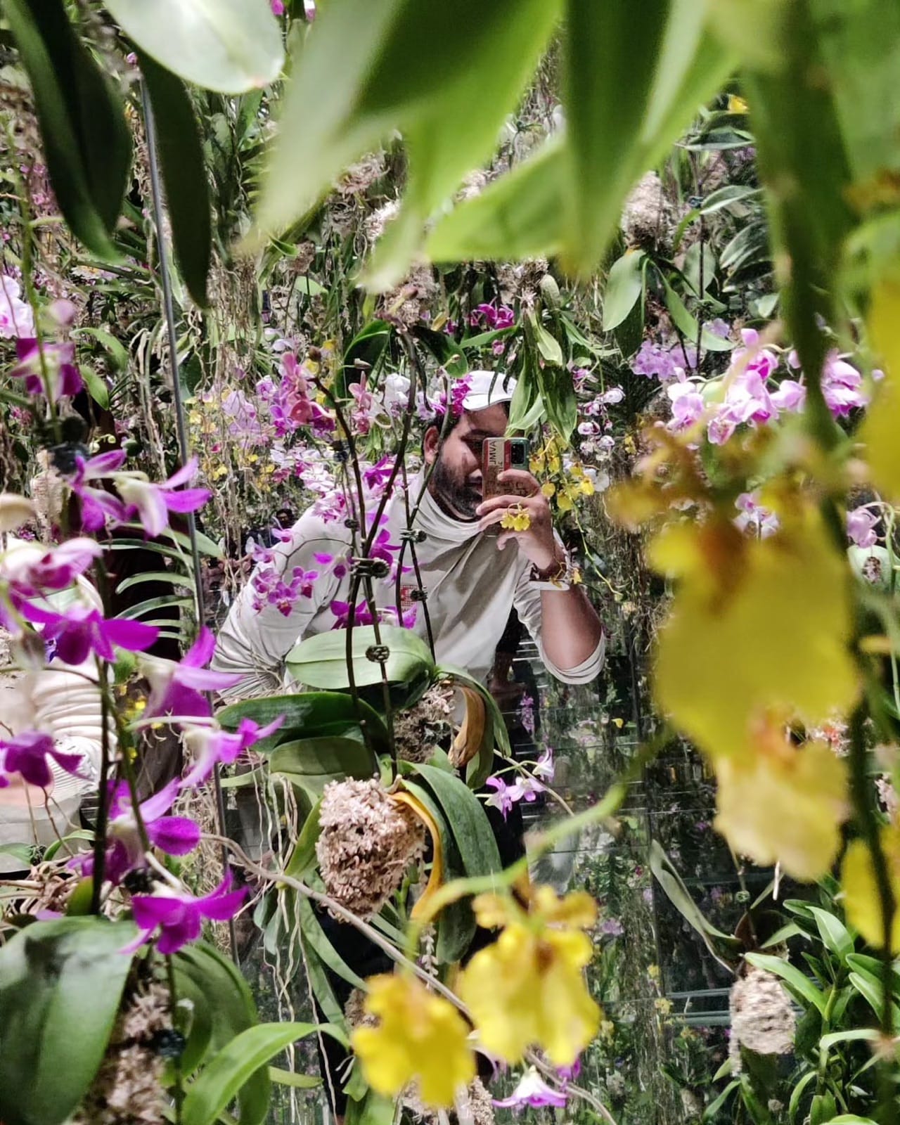 The author peeking through curtains of suspended orchids in the Floating Flower Garden at teamLab Planets