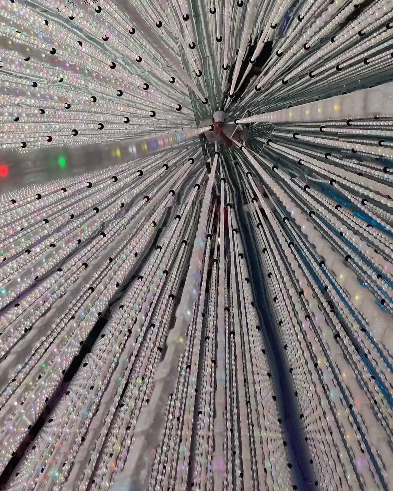 Crystal LED light strands radiating from an overhead point in the Infinite Crystal Universe at teamLab Planets