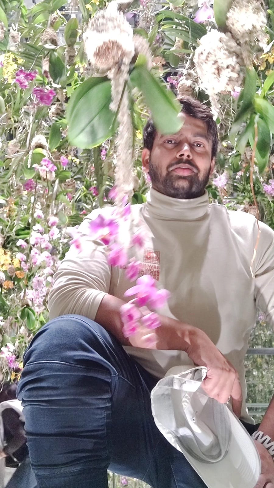 Portrait of the author seated among suspended pink orchids in the Floating Flower Garden at teamLab Planets