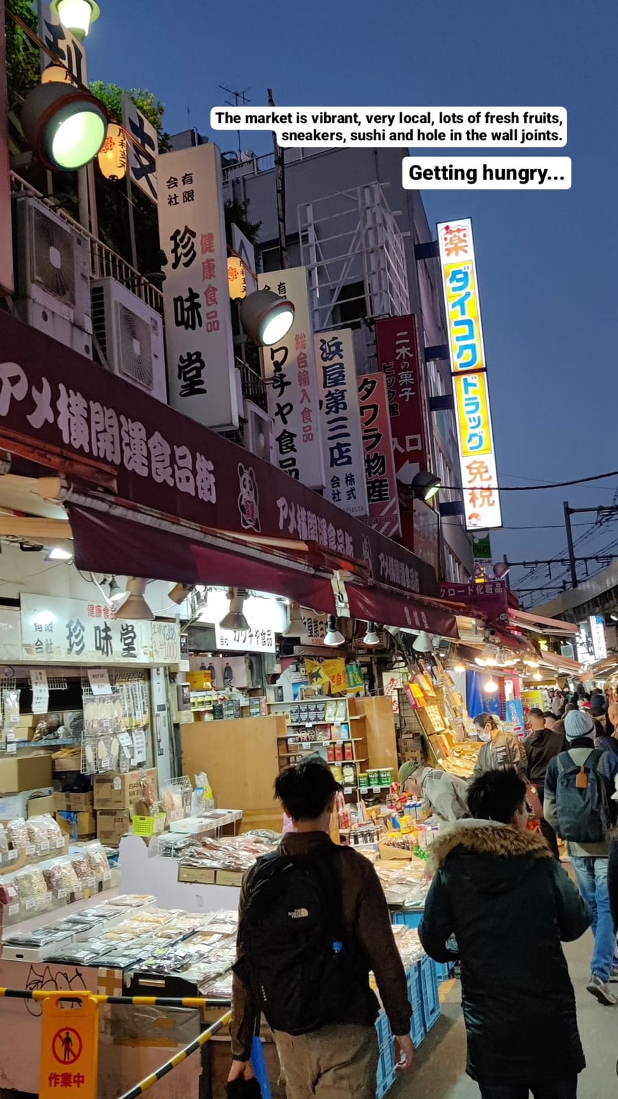 Market stalls with signage, crowds browsing.