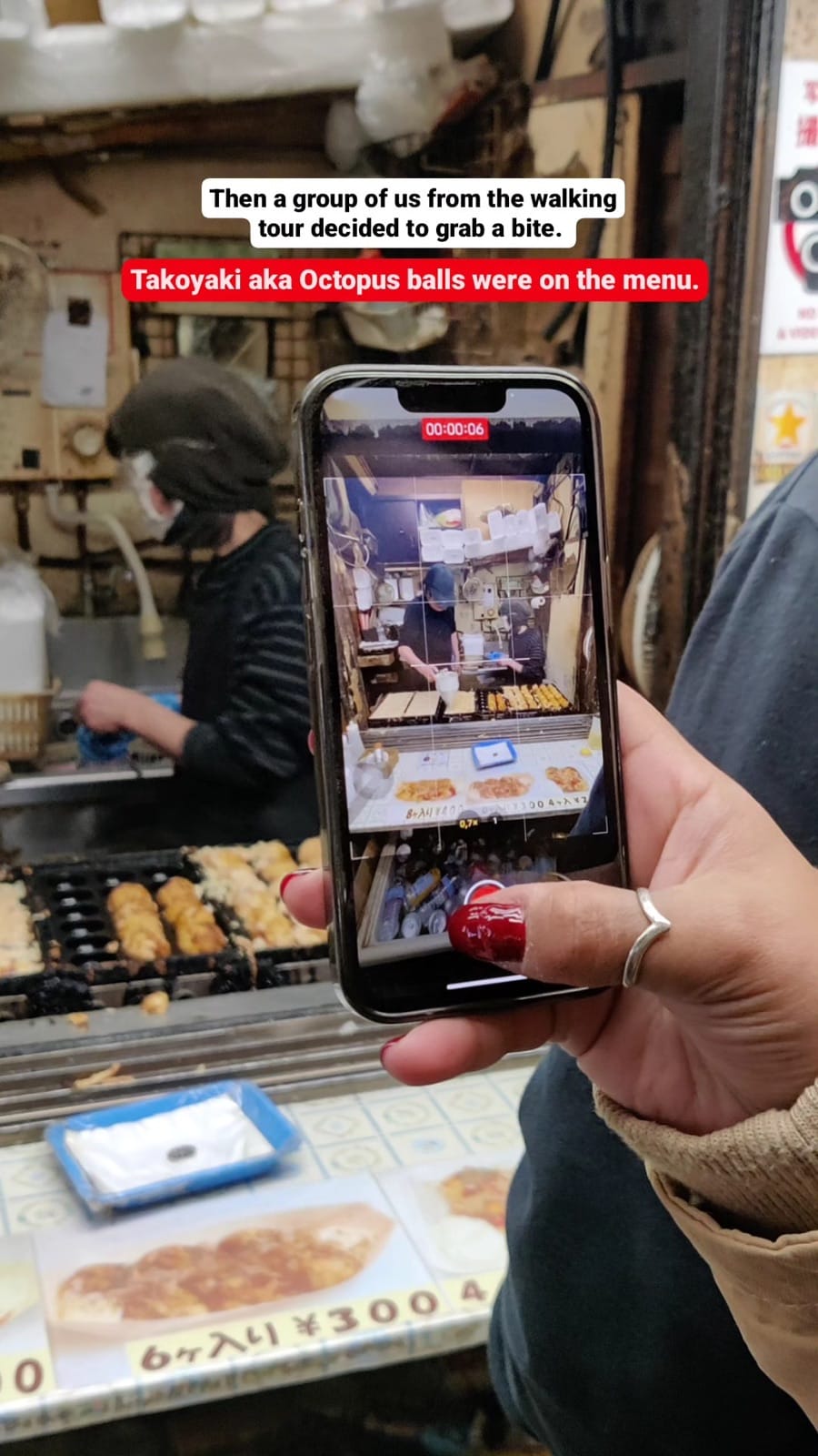 Group at takoyaki shop; phone filming the cooking process.