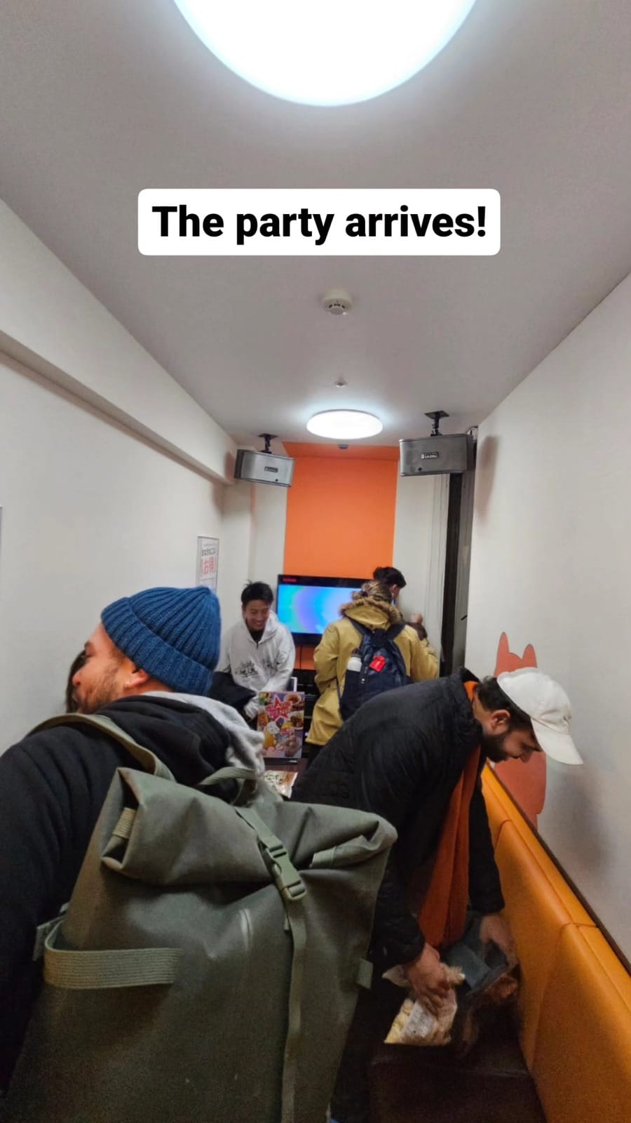 Group crowded in small karaoke room.