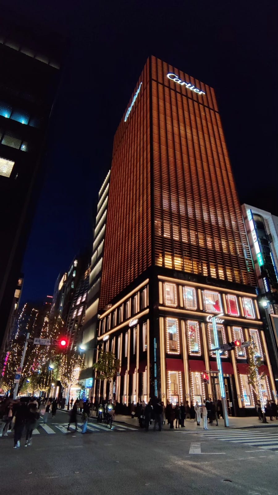 The amber-lit Cartier building in Ginza at night with illuminated Christmas window displays