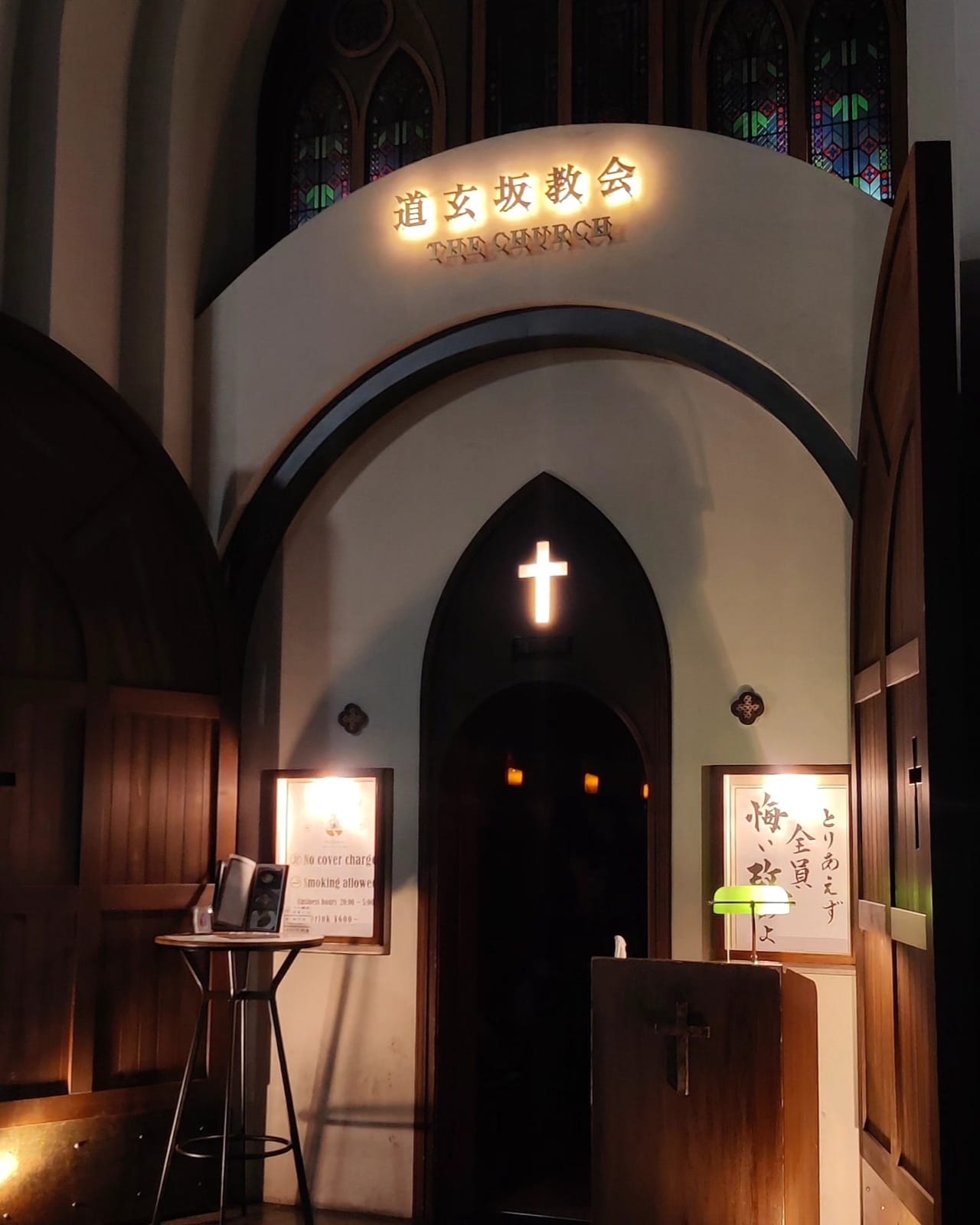 The gothic candle-lit entrance of the Dogenzaka Church bar in Shibuya with a glowing cross