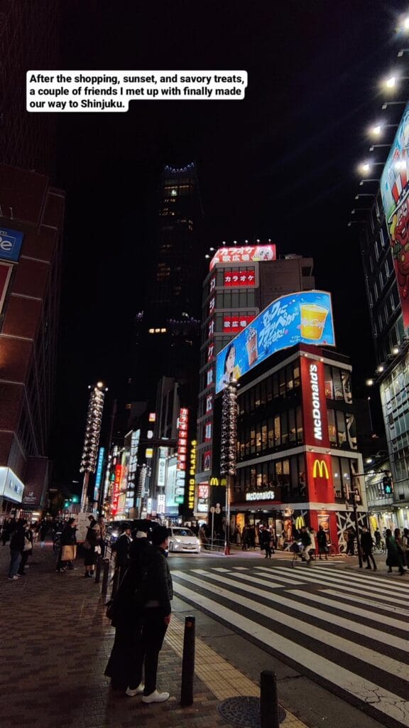 Tall building framed between neon signs and storefronts in Shinjuku