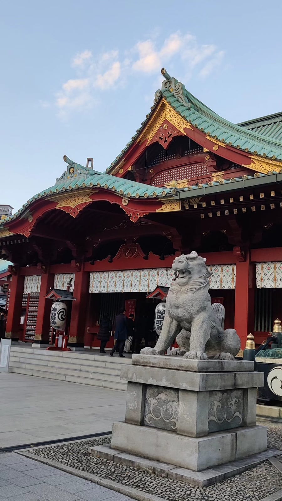 Stone komainu guardian lion in front of the vermilion main hall of Kanda Myojin shrine near Akihabara