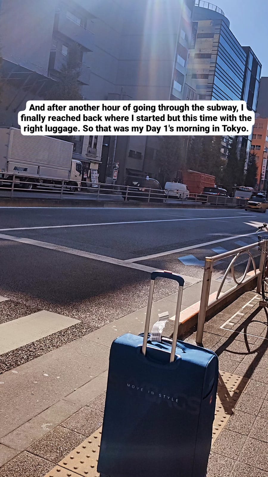 The author's own blue suitcase reclaimed and standing on a sunlit Asakusa street corner