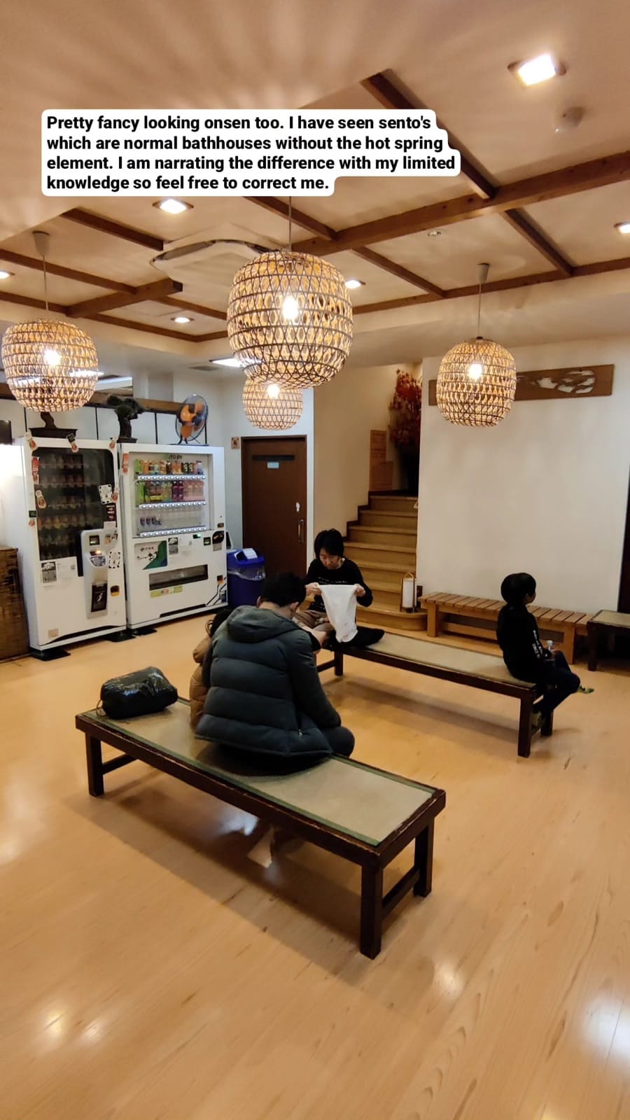 Warm wooden onsen lobby with rattan pendant lanterns and benches at a Tokyo bathhouse