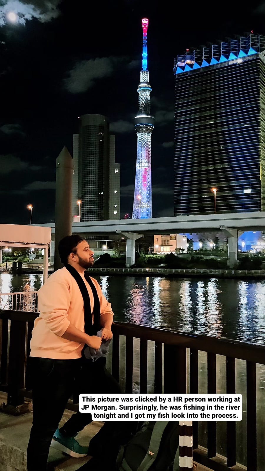 The author leaning on a Sumida River railing at night with Tokyo Skytree glowing behind him