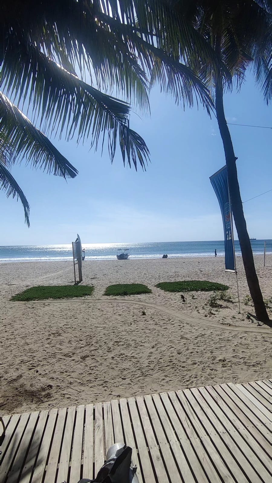 Uppuveli beach framed by palm fronds from a dive centre boardwalk in Trincomalee