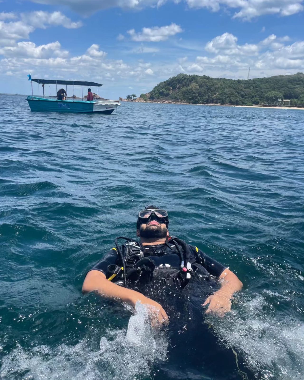Scuba diver floating on the surface next to a dive boat near Pigeon Island, Trincomalee