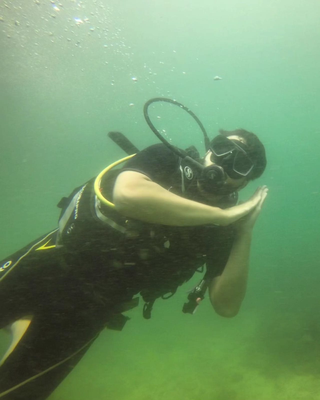 Scuba diver underwater pretending to sleep with hands under cheek near Pigeon Island