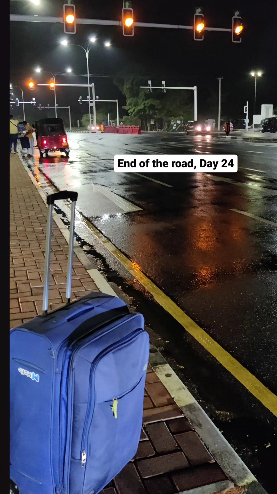 A blue suitcase on a rain-slicked Colombo street at night: end of the road