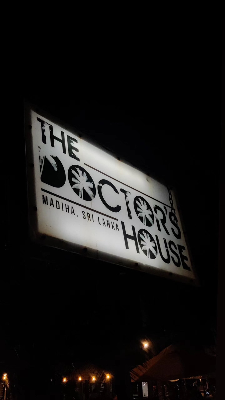The Doctor's House sign lit up at night in Madiha, Sri Lanka